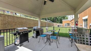 An outdoor patio with a grill, chairs, and tables.