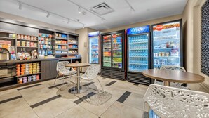A clean, modern convenience store with refrigerated beverage dispensers, snack shelves, and seating areas. - Candlewood Suites Dumfries - Quantico by IHG (Dumfries)