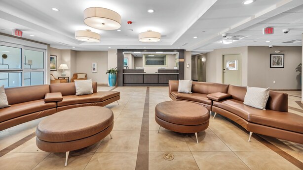 A modern lobby with brown leather sofas, a central coffee table, and pendant lighting. - Candlewood Suites Dumfries - Quantico by IHG (Dumfries)