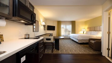 Habitación de hotel con kitchenette, cama, sofá y televisión.
