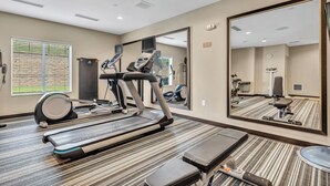 A hotel room with a treadmill, exercise bike, and a large mirror. - Candlewood Suites Dumfries - Quantico by IHG (Dumfries)