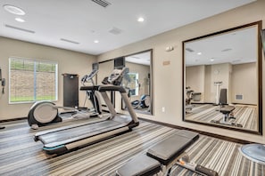 Ein Hotelzimmer mit Laufband, Ergometer und großem Spiegel.