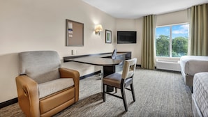 A hotel room with a desk, two chairs, a bed, a TV, and a window with curtains. - Candlewood Suites Dumfries - Quantico by IHG (Dumfries)
