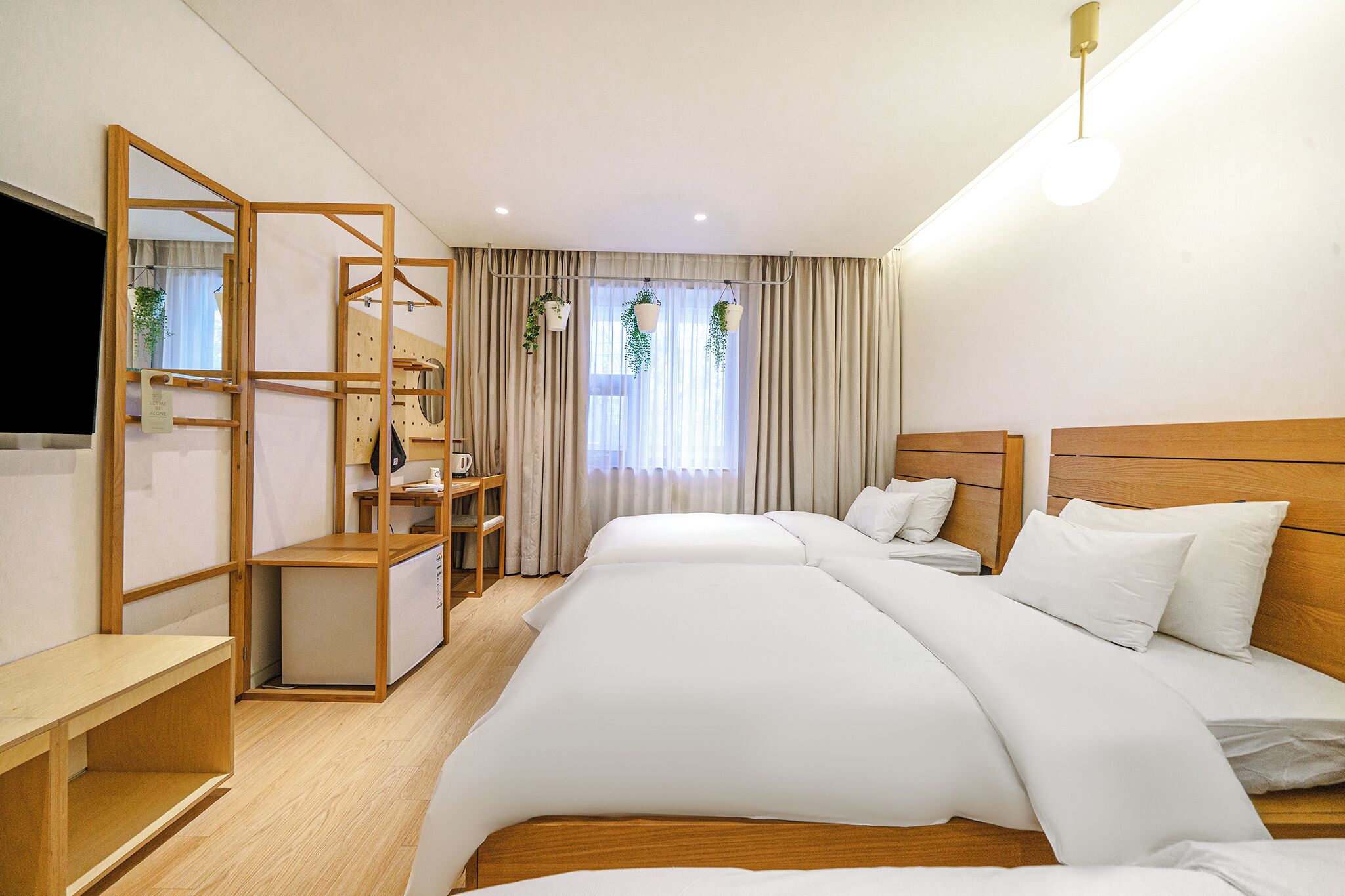 A hotel room with a bed, a desk, a chair, a TV, and a window with curtains.