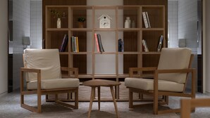 Una stanza moderna con due poltrone in pelle, un tavolino in legno e una libreria in legno con libri e oggetti decorativi.