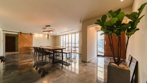 A spacious conference room with a long table and chairs, a large potted plant, and a view through the glass doors. - Chuncheon Hey Hotel (Chuncheon)