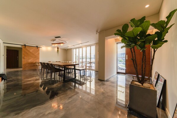 A spacious conference room with a long table and chairs, a large potted plant, and a view through the glass doors. - Chuncheon Hey Hotel (Chuncheon)