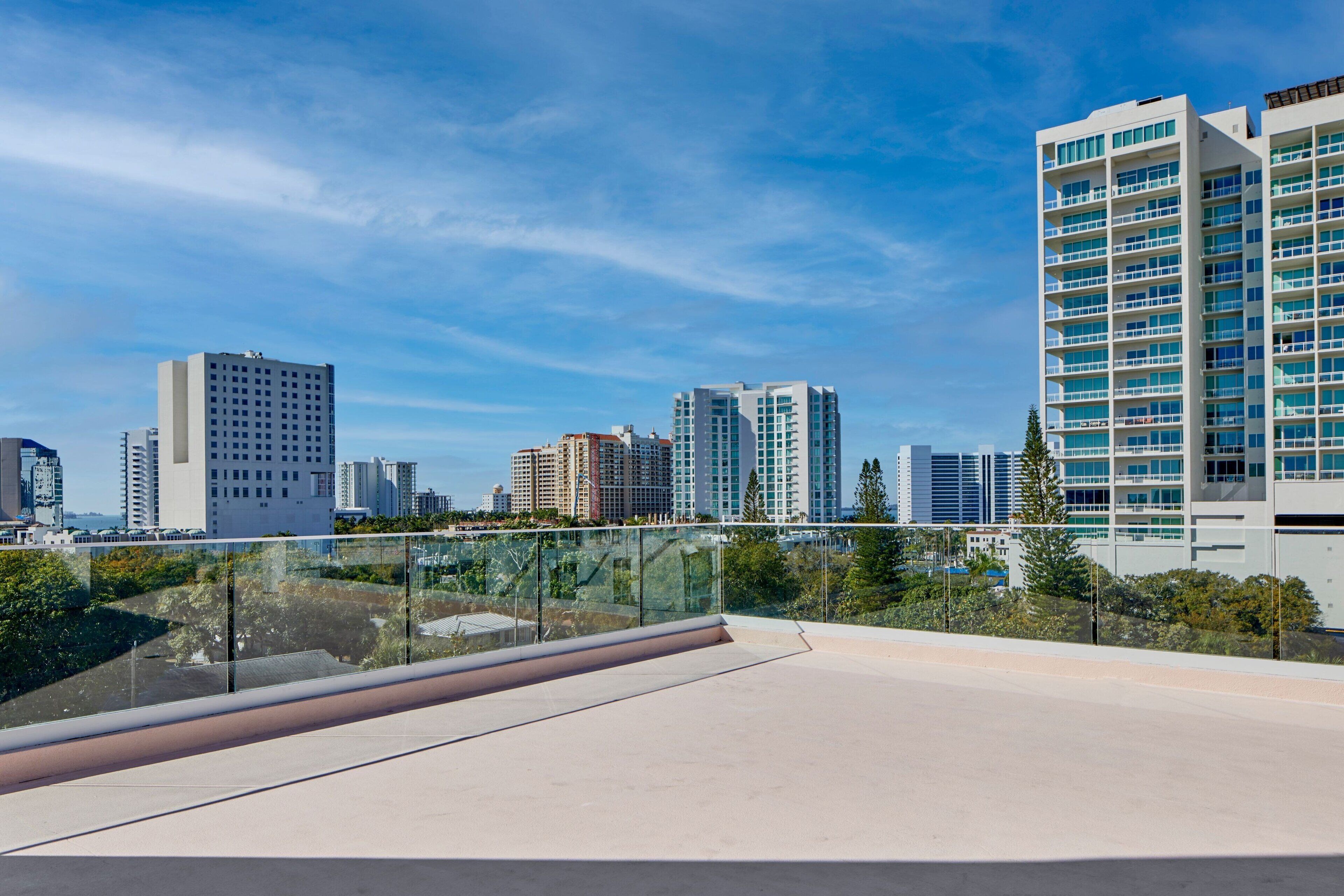A modern building with a glass facade and a flat roof, surrounded by other high-rise buildings.