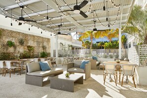An outdoor patio area with multiple seating arrangements, including sofas and chairs, and ceiling fans. - The Sarasota Modern, a Tribute Portfolio Hotel (Sarasota)