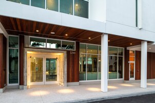 A modern building with a glass entrance, wooden paneling, and a number '1290' on the facade.