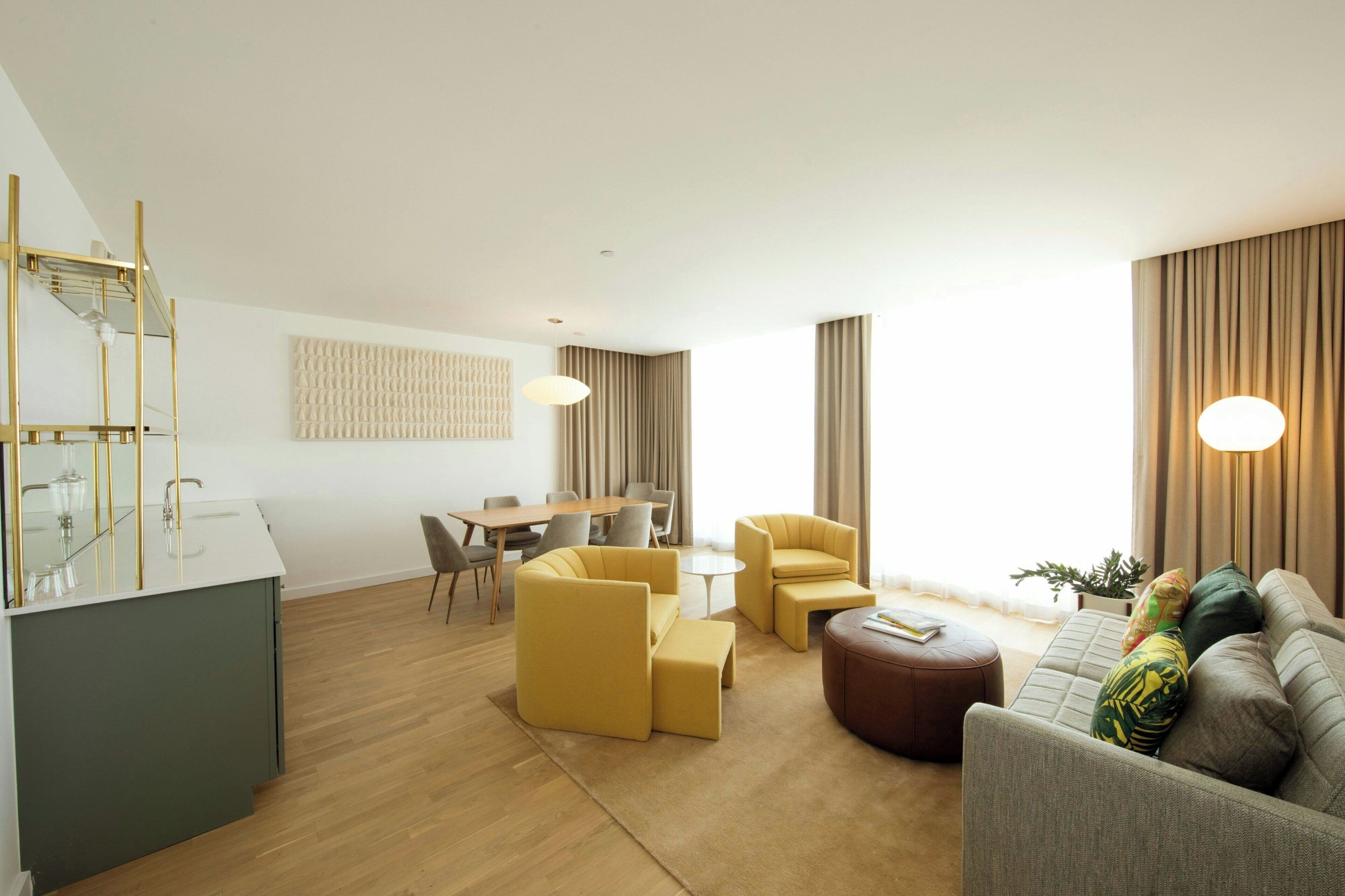 Un salon moderne comprenant un canapé, des fauteuils, un coin repas et une cuisine.