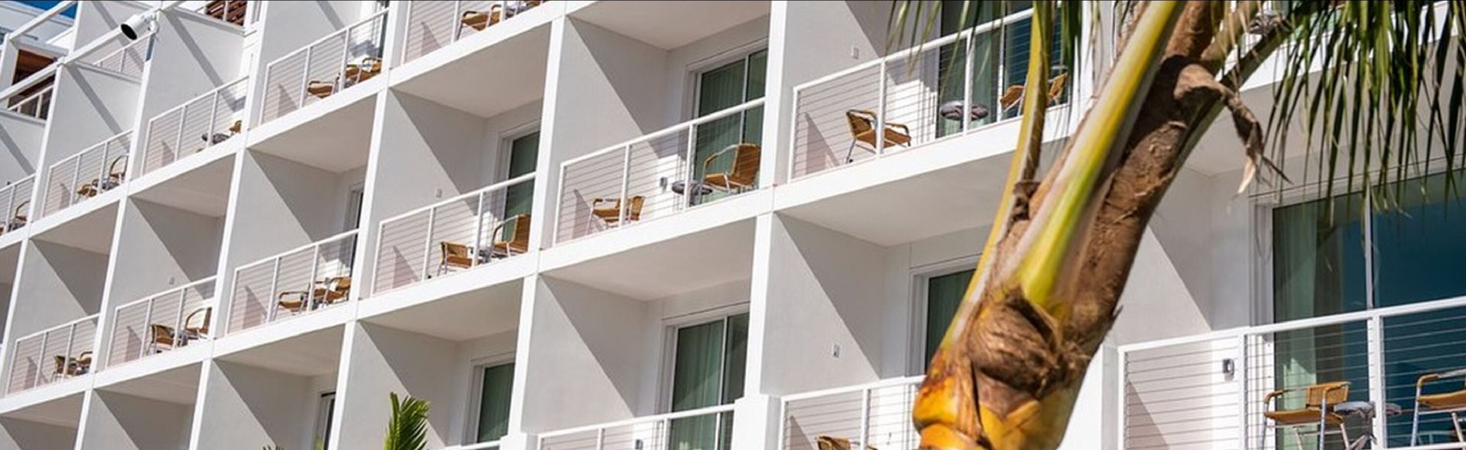 Un hôtel à plusieurs étages doté de balcons, chacun étant muni d’une rambarde et de chaises.