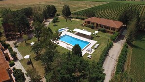 An aerial view of a property with a swimming pool, a garden, and vineyard fields. - Tenuta Lamborghini Golf & Resort (Panicale)