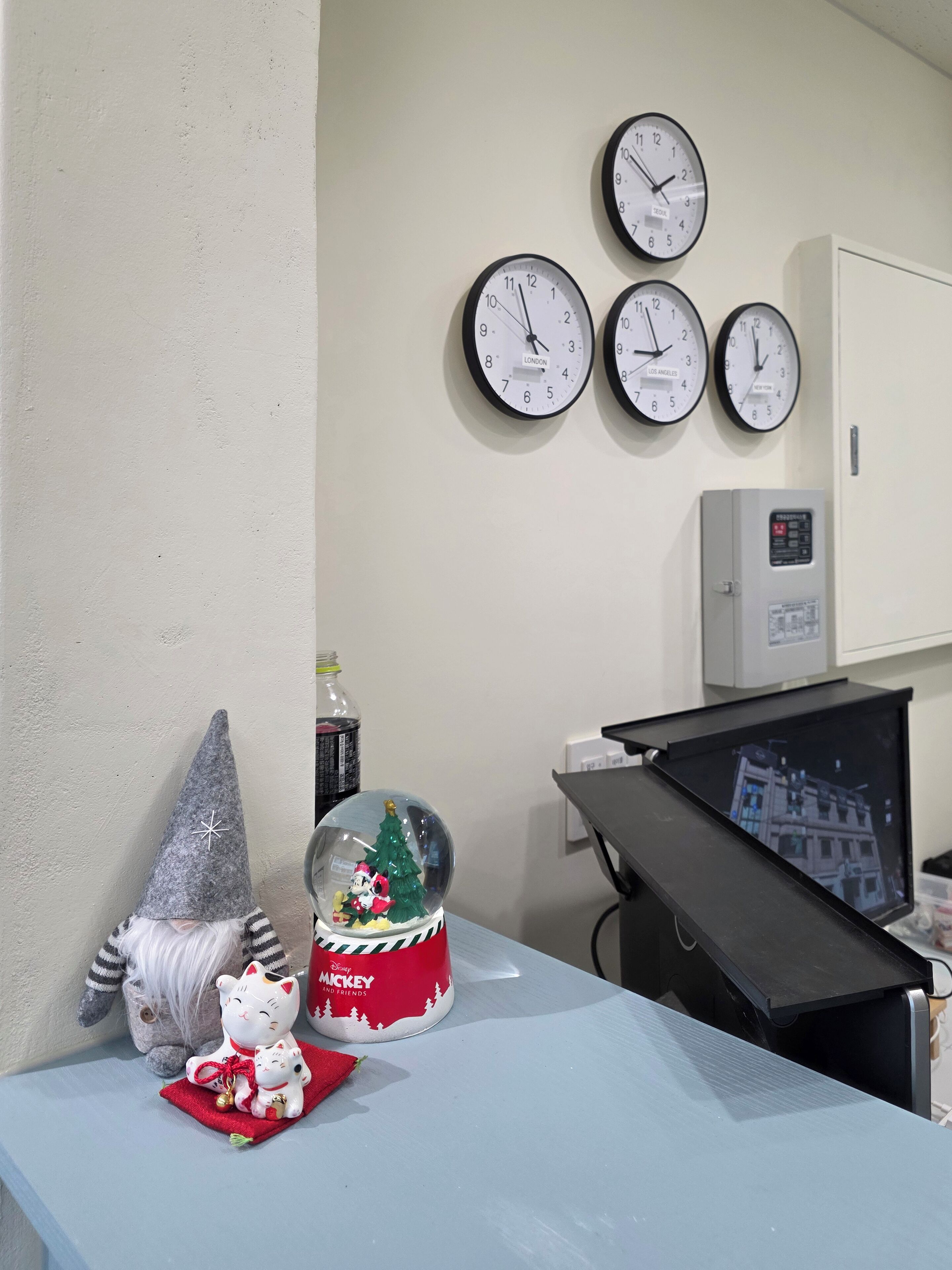 Une pièce comprenant un bureau, un écran d’ordinateur, une horloge et un globe à neige décoratif.