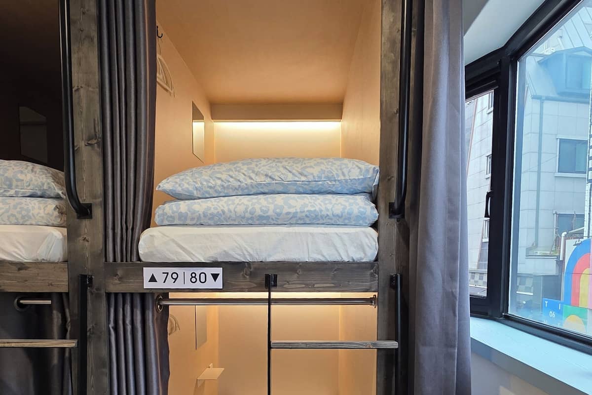 A bunk bed room with a window, a ladder, and a sign indicating the room number.