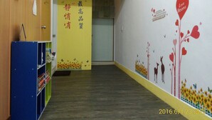 Una aula amb una paret groga, un tabló d'anuncis i un mural amb corrons i flors.
