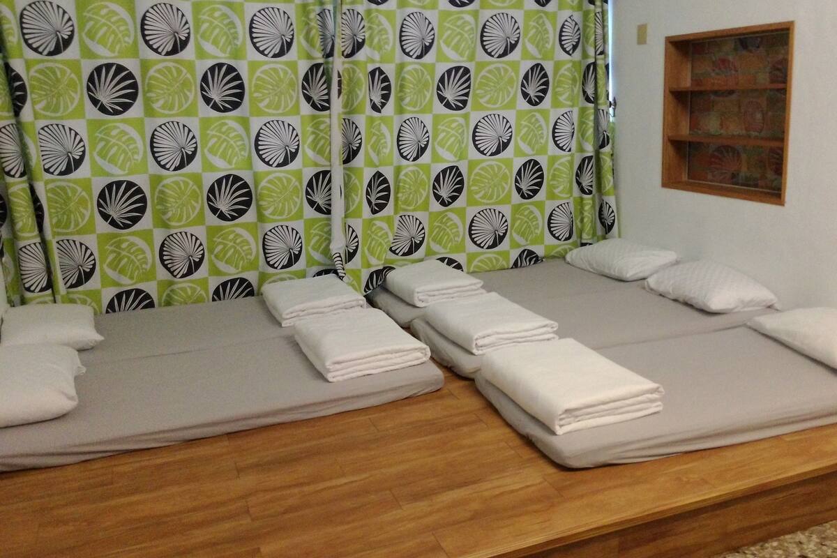 A room with two single beds, each with neatly folded white towels and pillows.