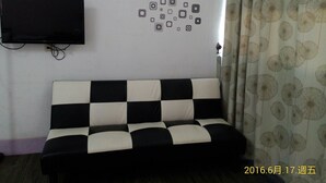 Una habitació amb un sofà de quadres negres i blancs, un televisor penjat i una cortina amb estampat floral.