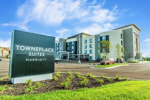 Señal de Towneplace Suites Marriott con un edificio moderno al fondo.