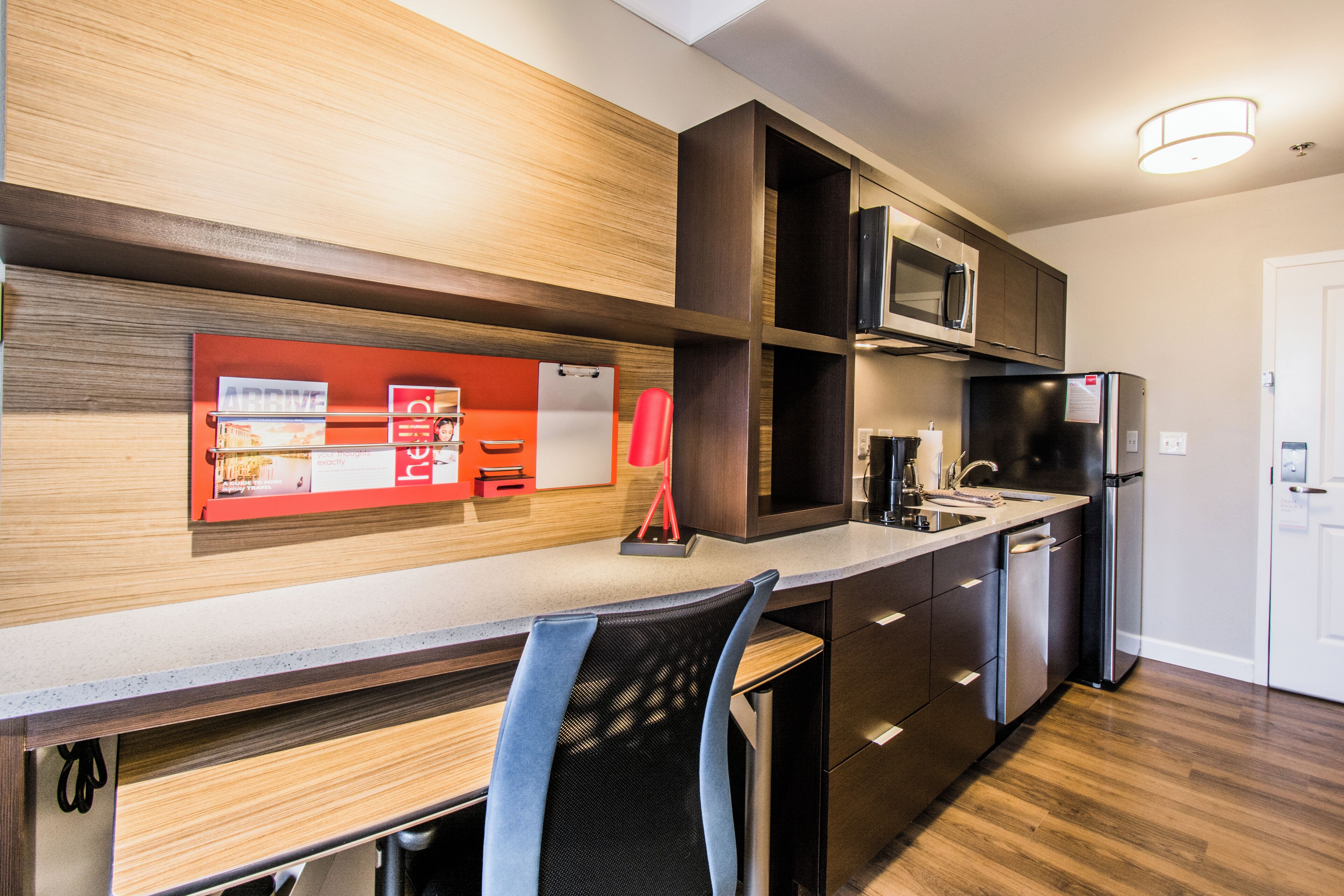 A modern kitchen with a wooden countertop, stainless steel appliances, and a red accent wall.