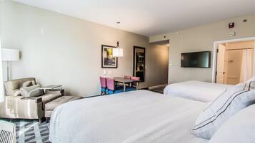 Una habitación de hotel con dos camas, un escritorio, una silla, un televisor y una puerta que da a un baño.