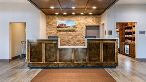 Una zona de recepción con pared de piedra, mostrador de madera y máquina expendedora.