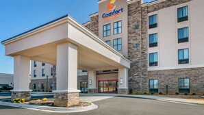 Un hotel Comfort Suites con fachada moderna, un acceso cubierto y una zona ajardinada en la parte delantera.