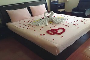 A neatly made bed with a swan and heart-shaped decoration, a chair, and a desk in a hotel room. - Sonya Residence (Patong)