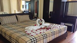 Uma cama com colcha xadrez, cabeceira escura e um espelho em cima.