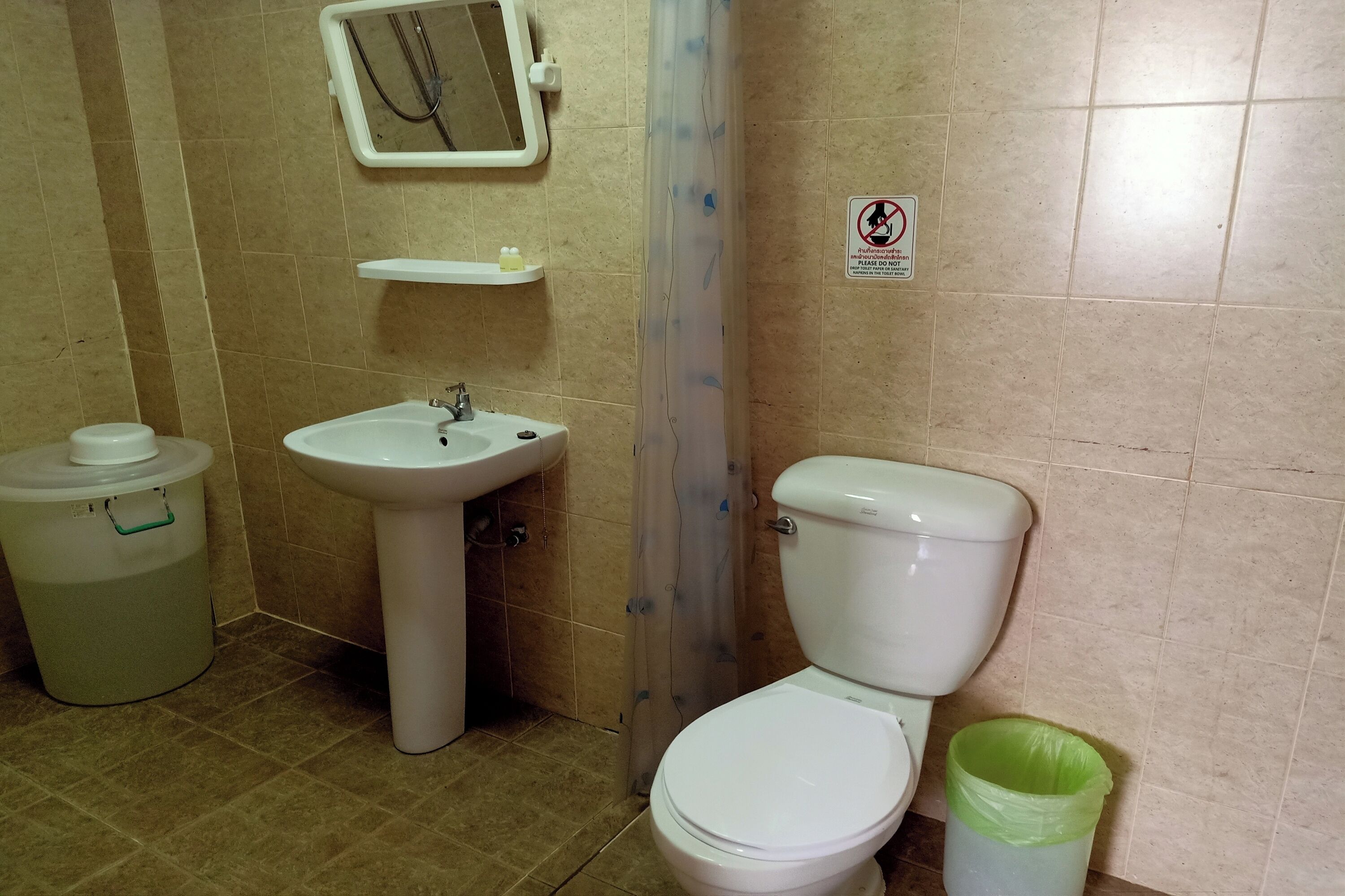 A bathroom with a sink, toilet, and a trash bin.
