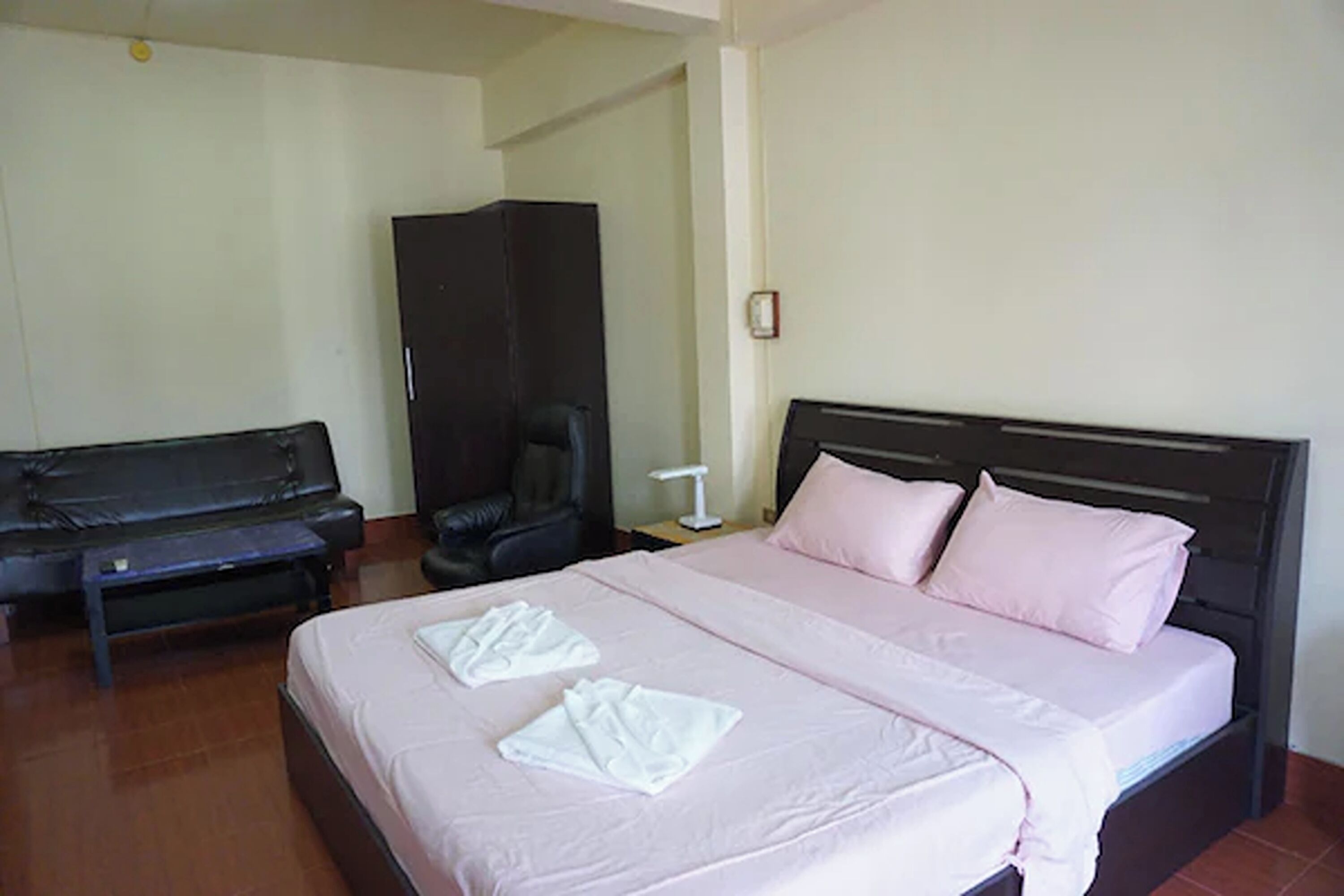 A hotel room with a bed, a sofa, a chair, and a wardrobe.