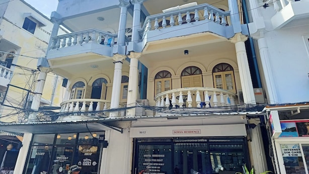 Um edifício de dois andares com varanda, café e placa de residência.