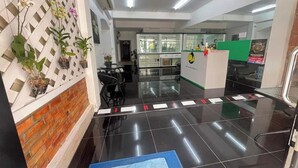 Uma área de recepção com balcão, cadeiras e divisória de vidro.