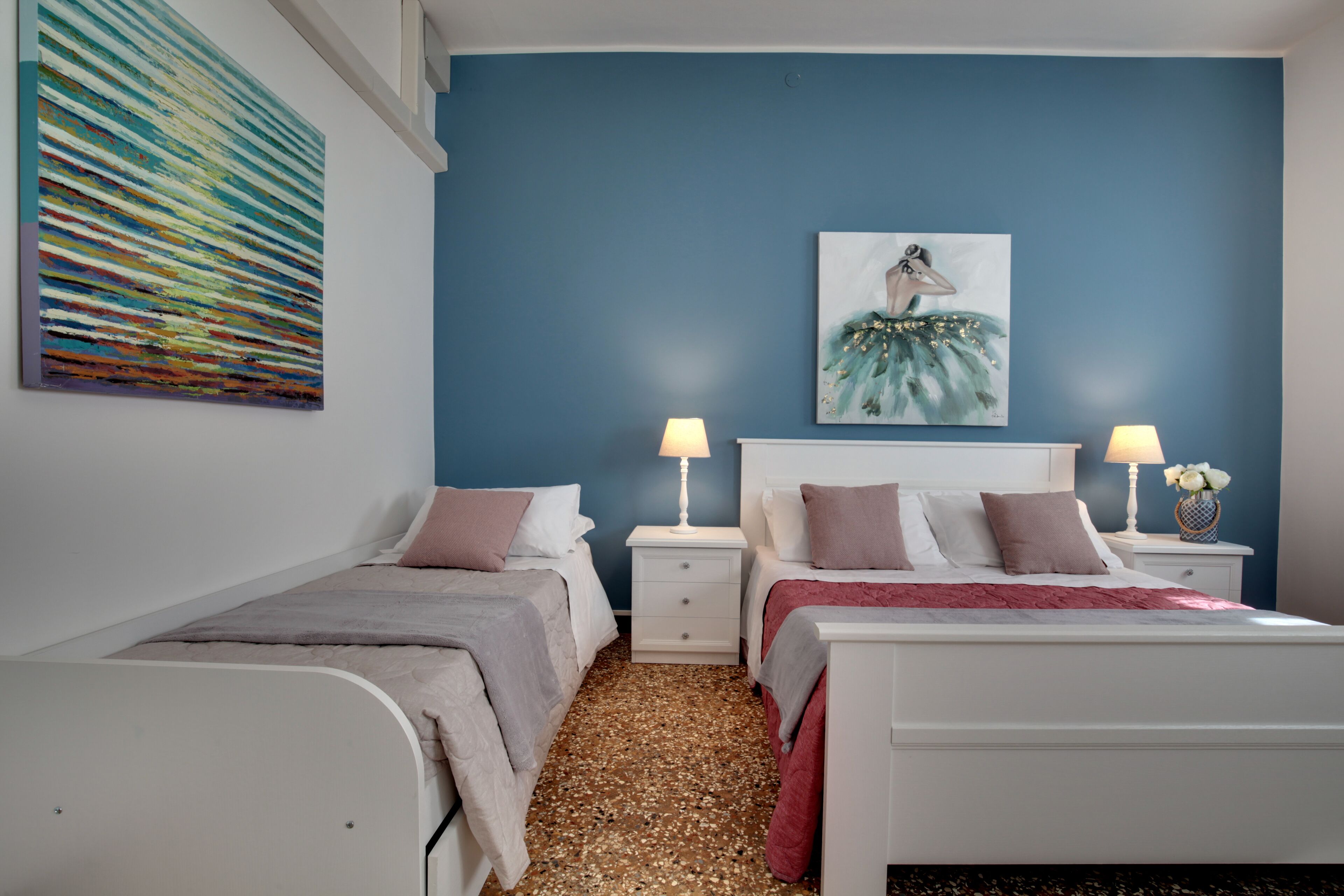 Une chambre avec deux lits, un mur d’accent bleu et des œuvres d’art.