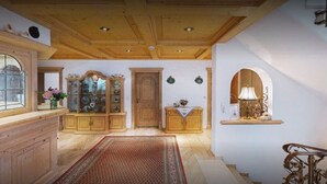Une pièce spacieuse dotée d’un plancher en bois, d’une grande armoire en bois, d’une vitrine et d’un escalier orné de balustrades décoratives.