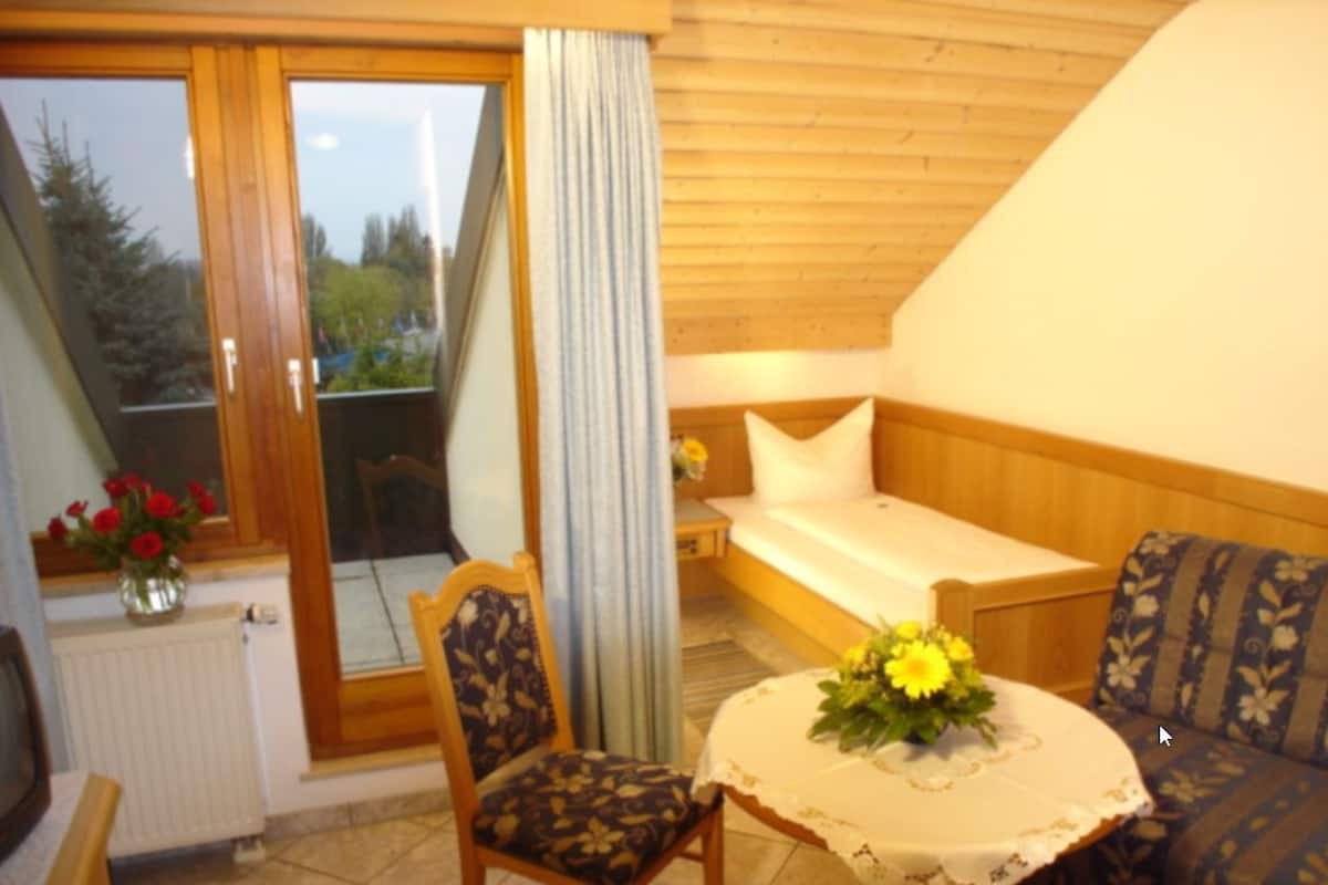 A cozy room with a wooden ceiling, a sofa, a table with a floral centerpiece, and a chair.