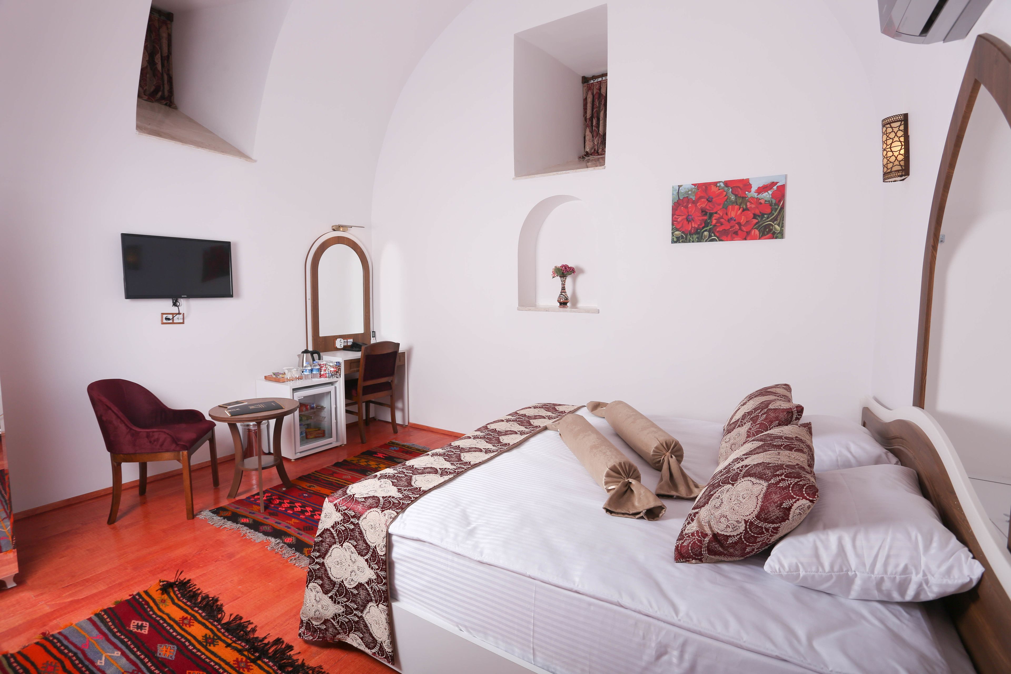 Une chambre avec un lit, un bureau, une chaise, une télévision et une petite fenêtre.