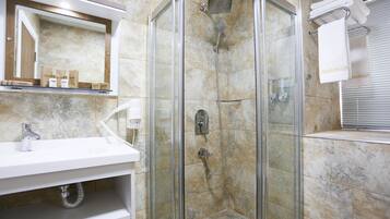 A modern bathroom with a glass-enclosed shower, a white sink, and a mirror above the counter.