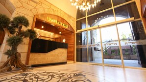 Una zona de recepción con mostrador de madera, candelabro y ventanas amplias.