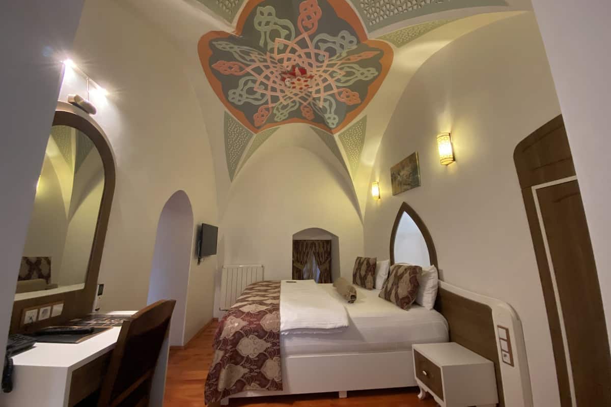 Une chambre à coucher avec un lit, un bureau et une chaise. Un grand élément décoratif orne le plafond au-dessus du lit.