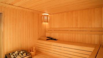 Uma sauna de madeira com bancos, um aquecedor e um balde.