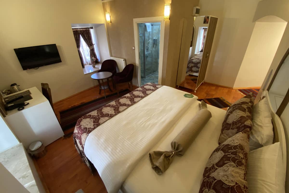 Une chambre d’hôtel avec un grand lit, un bureau avec une chaise, une télévision et un miroir.