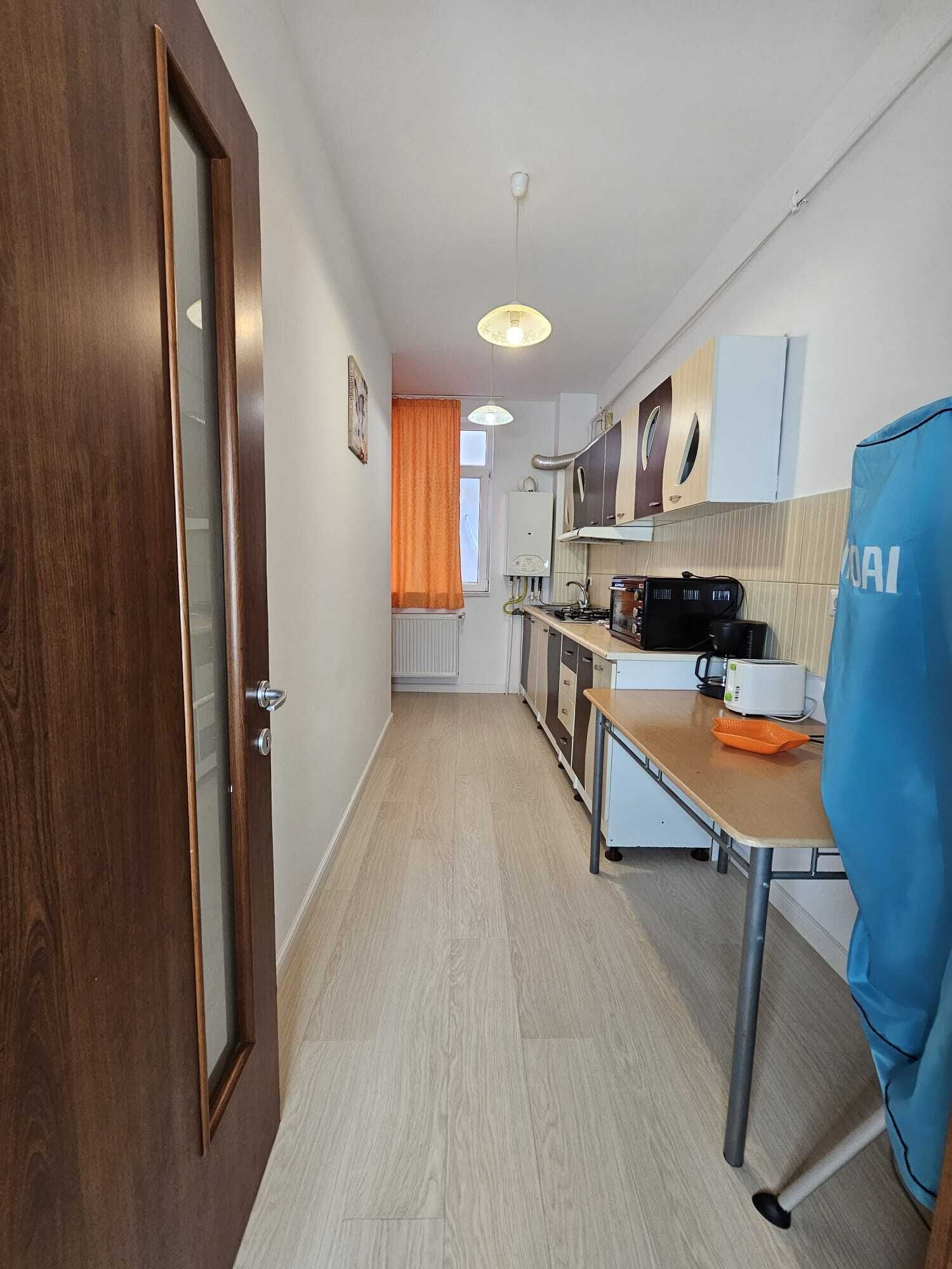 A narrow hallway leading to a kitchen with a microwave, stove, and cabinets.