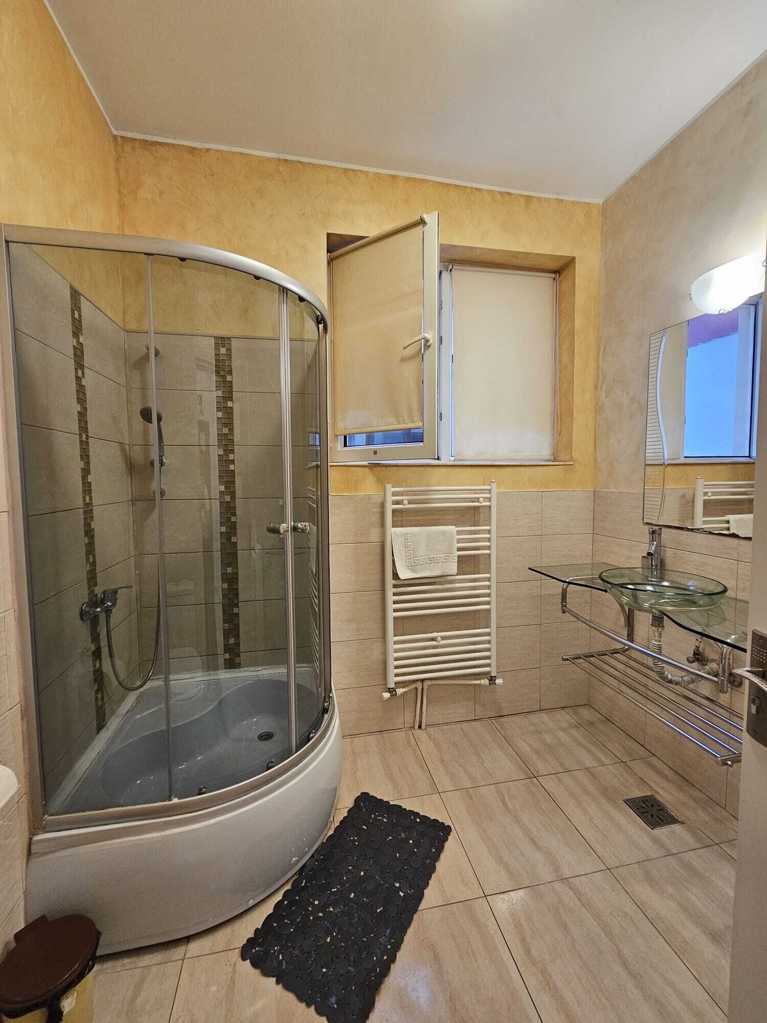 A modern bathroom with a glass-enclosed shower, a glass sink, and a towel rack.