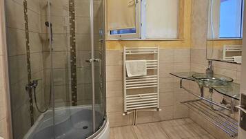A modern bathroom with a glass-enclosed shower, a glass sink, and a towel rack.