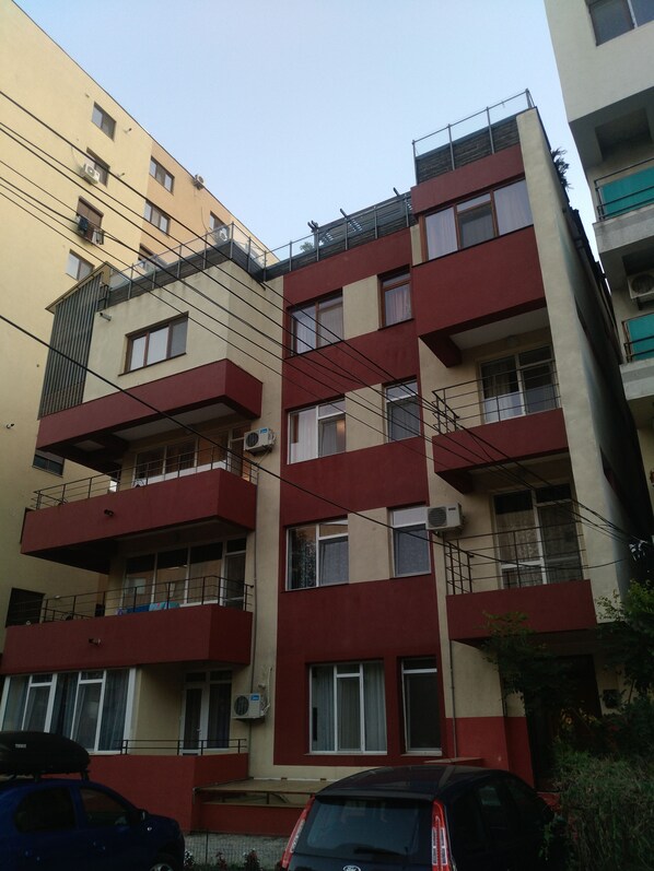A multi-story residential building with balconies, air conditioning units, and a parked car in front. - Gabizz Apartments (Constanta)