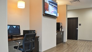 A hotel reception area with a desk, computer, chair, and a television displaying a news channel. - Sleep Inn & Suites Oregon - Madison (Oregon)