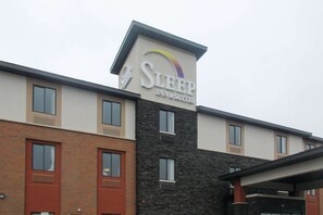 A Sleep Inn & Suites building with a modern design, featuring a mix of brick and stone facades, multiple windows, and a prominent signage.