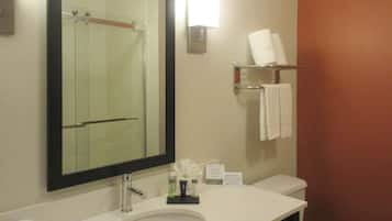A hotel bathroom with a sink, mirror, towel rack, and a sign with information.