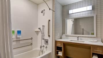 A modern bathroom with a bathtub, a shower, a vanity with a mirror, and a towel rack.